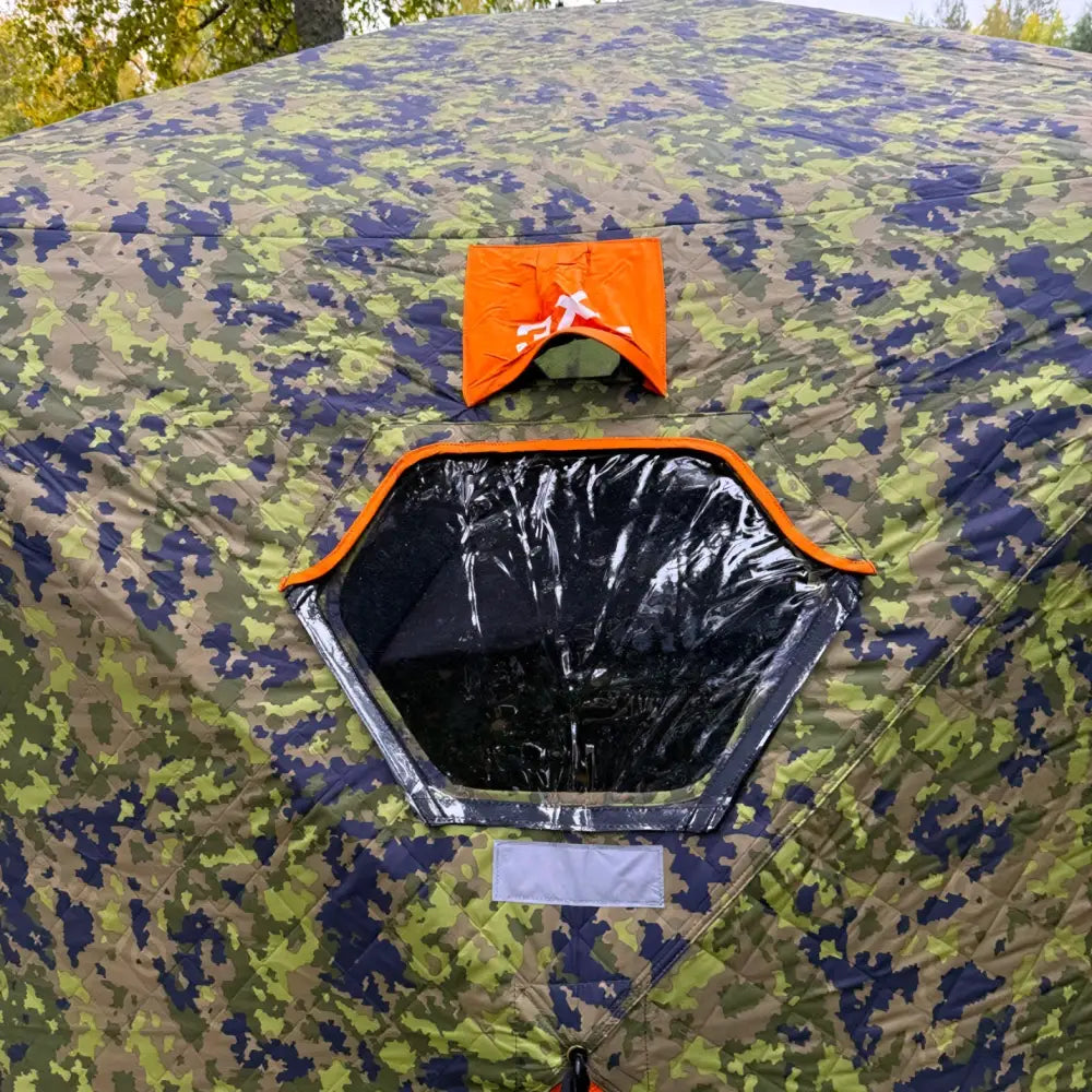 Camouflage-kuvioitu Haghus Bushman 3XL metsästysteltta oranssilla ikkunaluukulla ja kuusikulmaisella verkkoikkunalla