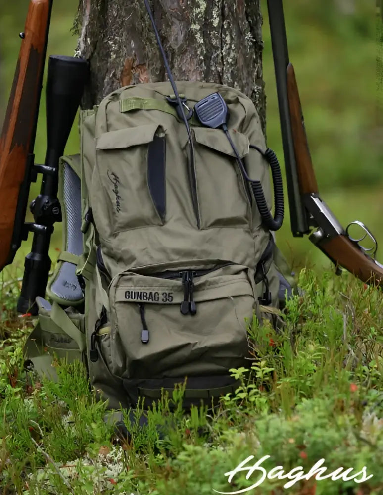 Olivegreen tactical backpack with black zippers labeled gunbag 35 featuring multiple compartments and a mounted radio from haghus korpimäki 35 päivärinkka asepussilla