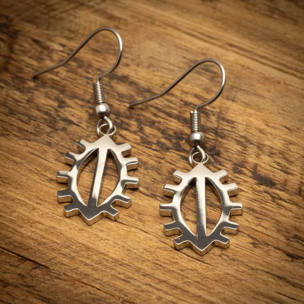 Silveriset kirkkovene korvakorut metallisella pinnalla ja monimutkaisella ratashampaisella kuvioinnilla