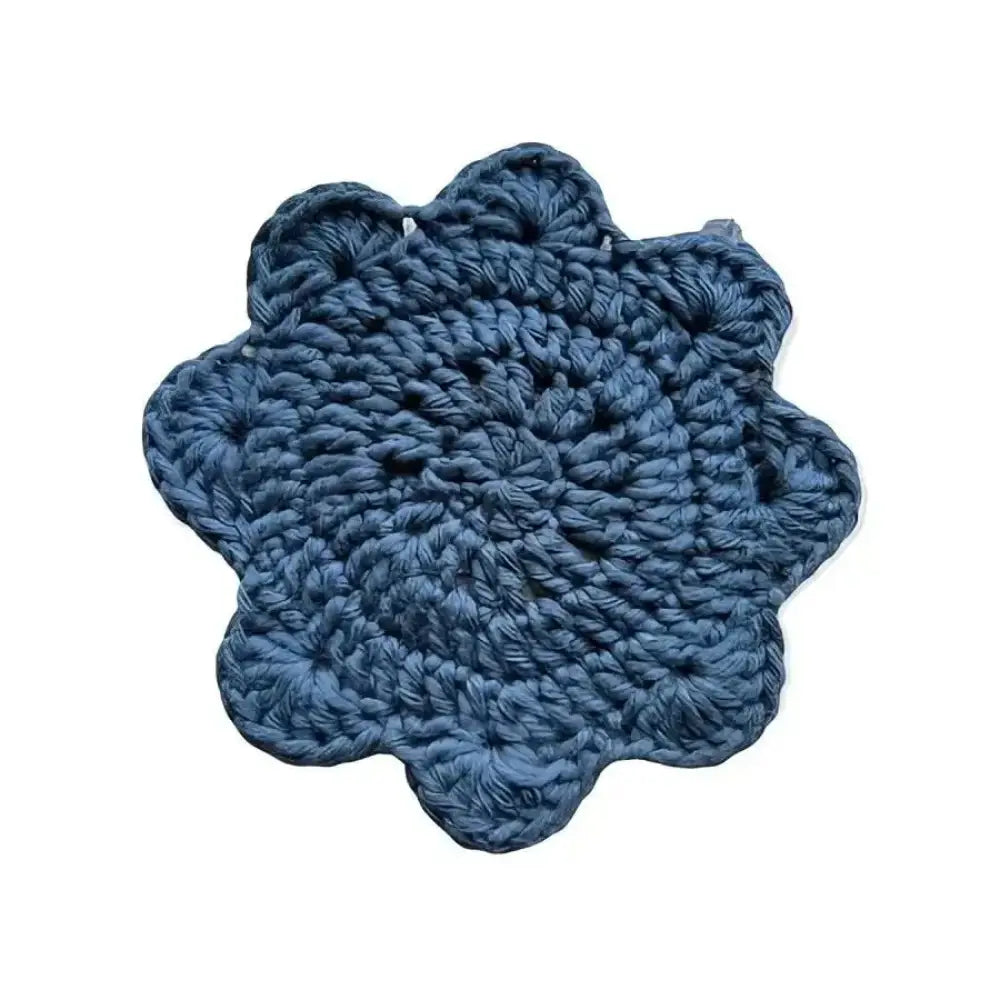 A hand-crocheted lasinalunen coaster in deep blue with a scalloped edge and textured pattern