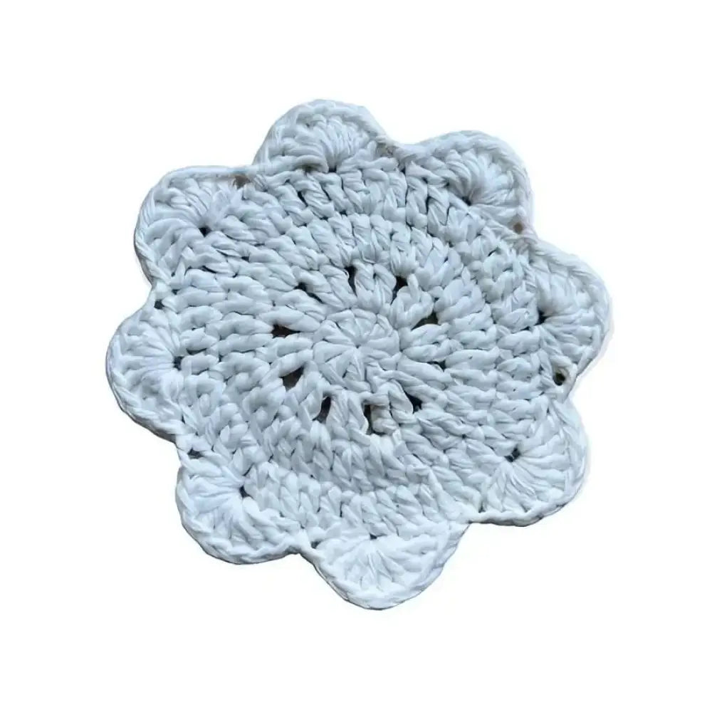 A delicate white crocheted coaster with a floral petal-like design for lasinalunen crochet