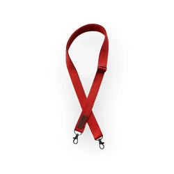 Punainen nailoninen laukun olkahihna mustilla metalliklipsuilla ja ruskealla nahkatarralla puuvillainen
