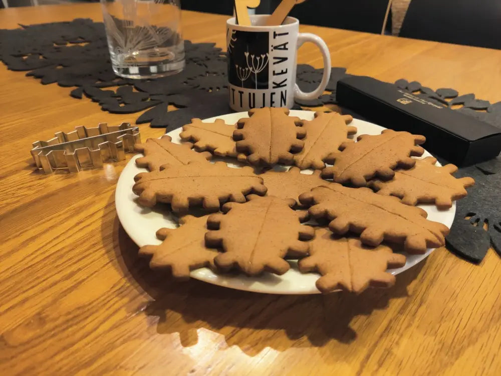 A plate of golden brown leaf shaped gingerbread cookies arranged in a circular pattern for piparipiparimuotti