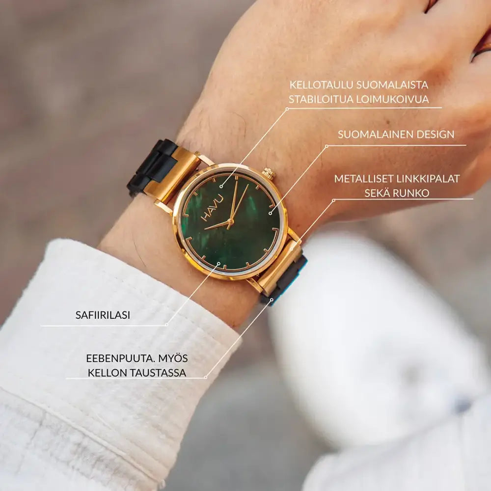 A sleek gold-toned revontuli eebenpuu 40mm watch with a deep green textured dial and black rubber strap on a wrist