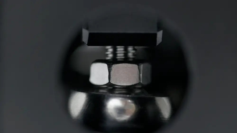 Black hexagonal bolt with matching nut and threaded shaft viewed through reflective spherical lens in simagic q1 sequential shifter