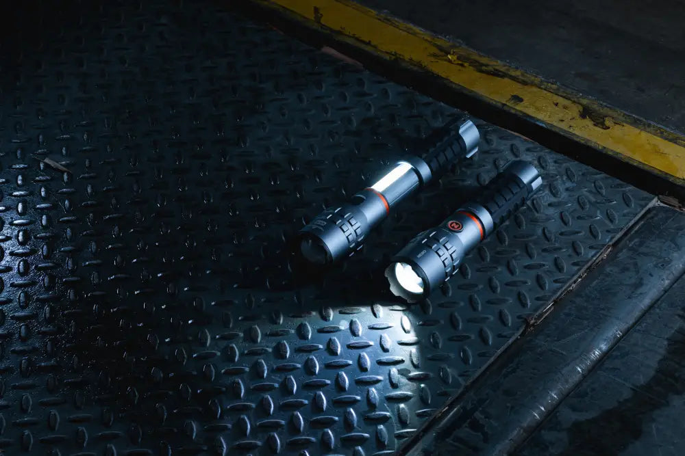 Two black slyde king 4k tactical flashlights with textured grips and orange accent rings on diamond plate surface