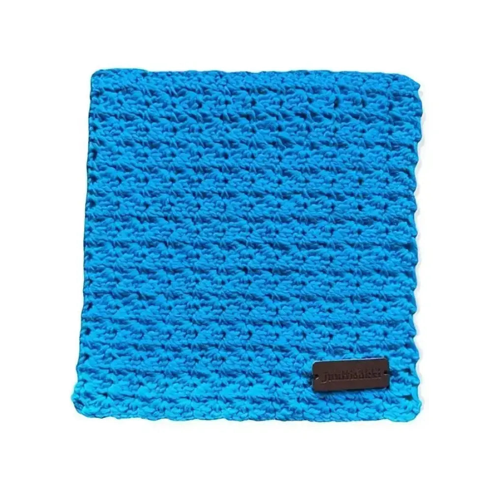 Bright blue crocheted tiskirätti sikin sokin dishcloth with textured pattern and small brown leather tag at corner