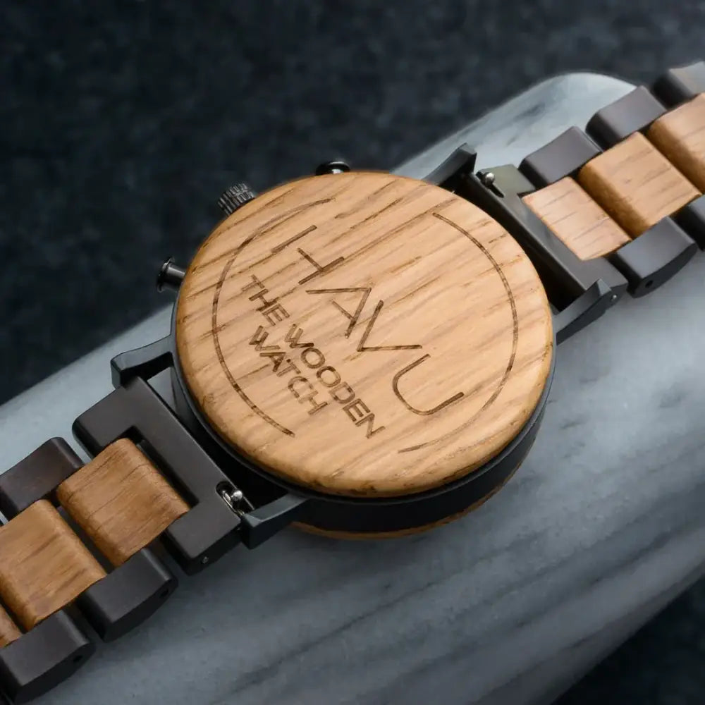 A elegant wooden vuori watch with a light brown wood face, black metal links, engraved havu brand and the wooden watch text