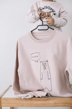 A soft blush pink oversized college sweatshirt featuring a black line-drawn bear with you are hot text in a speech bubble
